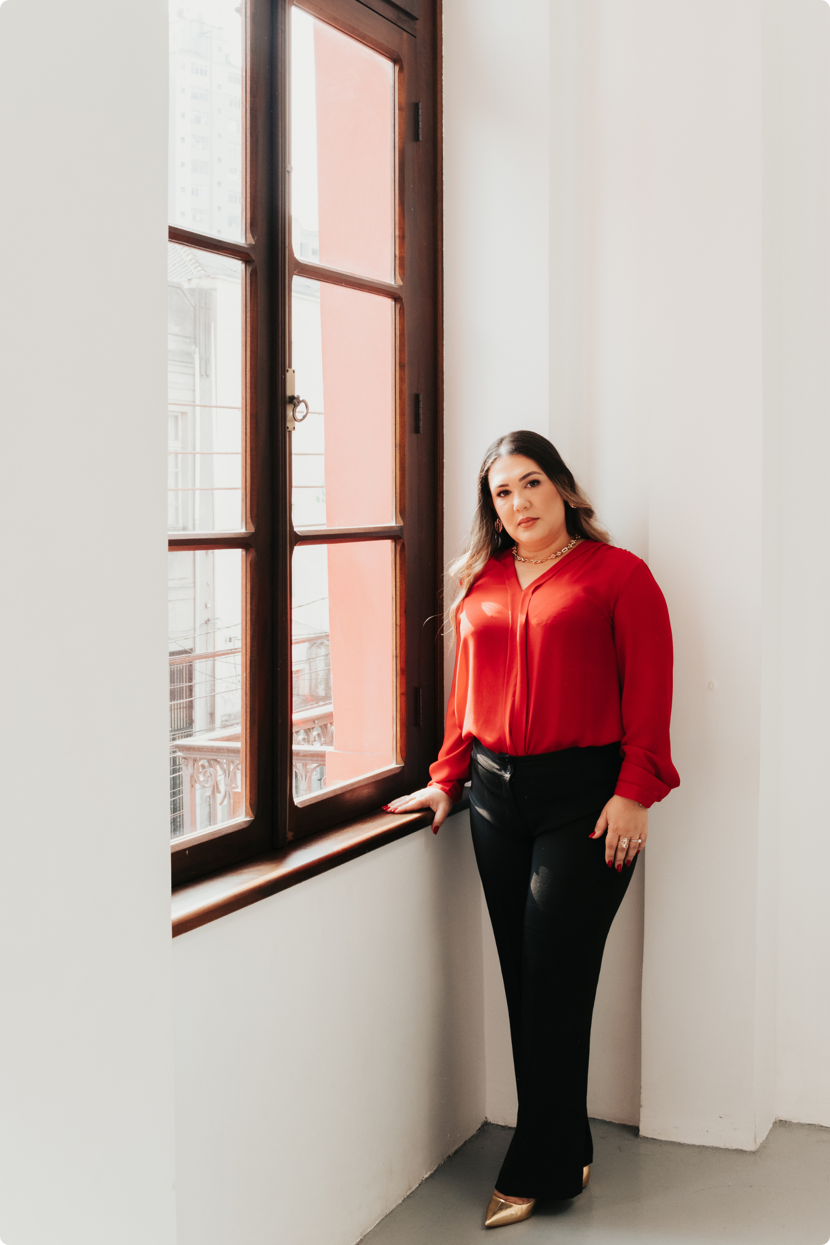 Advogada Kharen Horsts ao lado de uma janela, expressão confiante e receptiva, simbolizando atendimento personalizado em Direito Imobiliário.