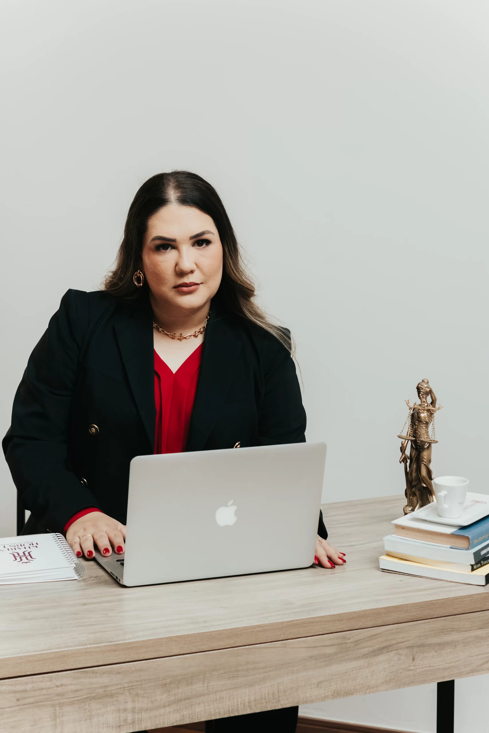 Foto da advogada Kharen no escritório, usando notebook, representando a consultoria em empresas e imóveis.