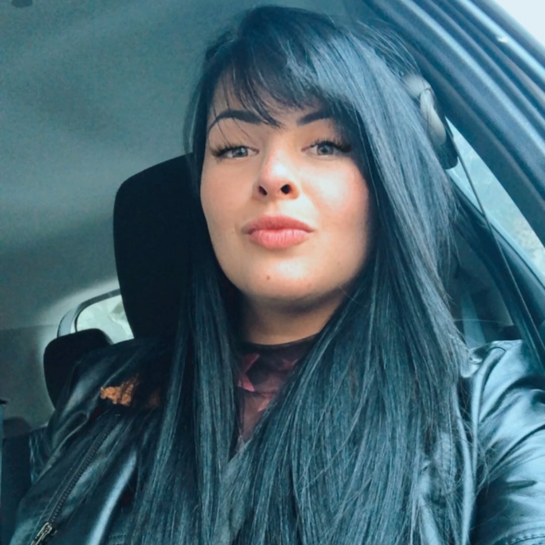 Cliente satisfeita em selfie no carro; avaliação 5 estrelas sobre atendimento humanizado.